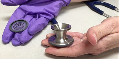 Hands holding a 3M™ Littmann® Classic III™ Stethoscope chestpiece and removable single-piece diaphragm.
